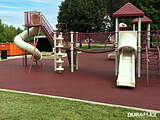 Park playground with poured-in-place rubber surfacing underneath the playset