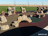 Rubber playground surface underneath artificial rocks